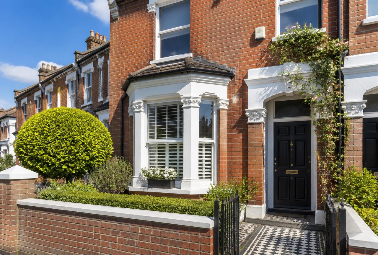 Victorian terraced house with a black front door, bay window and red brick facade